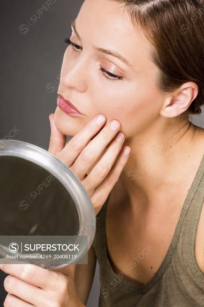 Woman checking her face in the mirror.