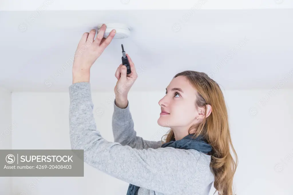Woman installing a smoke detector.