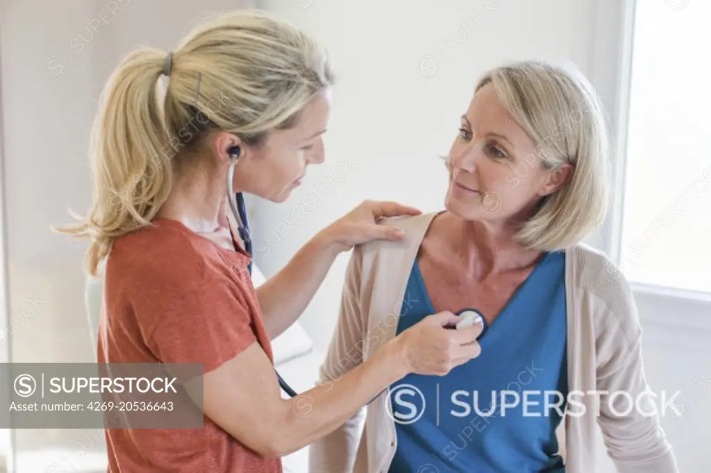 Doctor examining a female patient with a stethoscope.