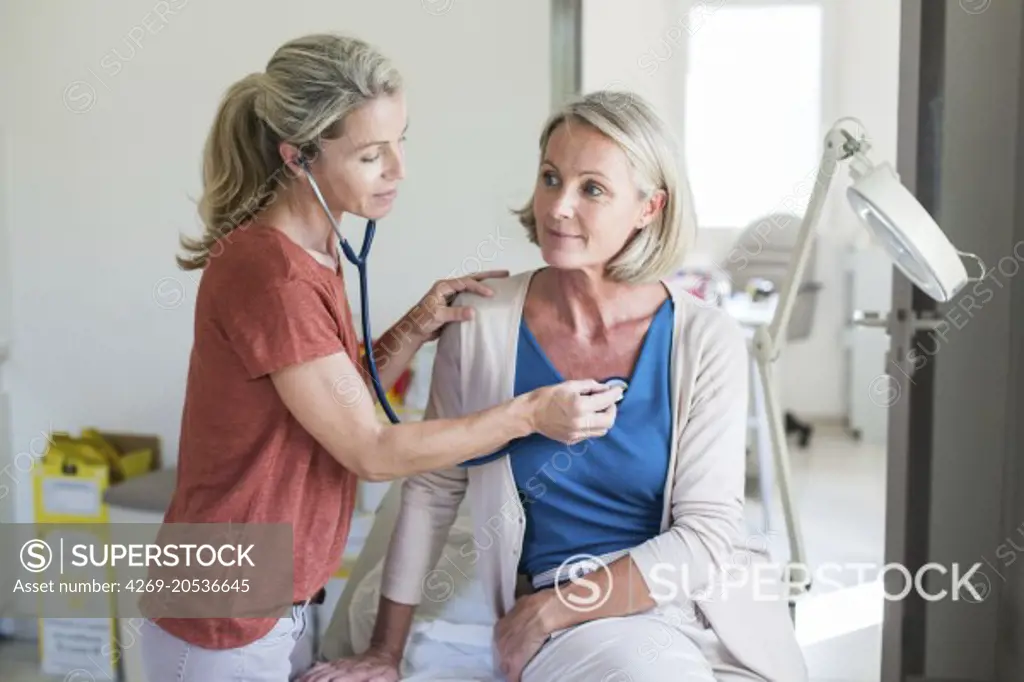 Doctor examining a female patient with a stethoscope.