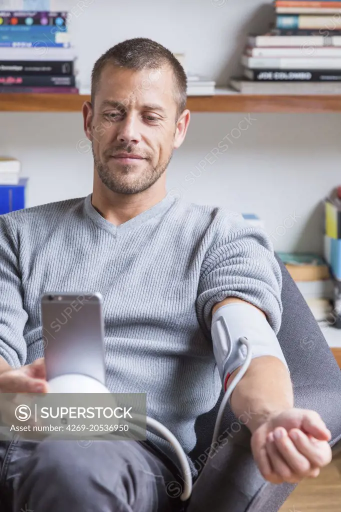 Man taking his blood pressure with a sphygmomanometer connected to his cell phone.