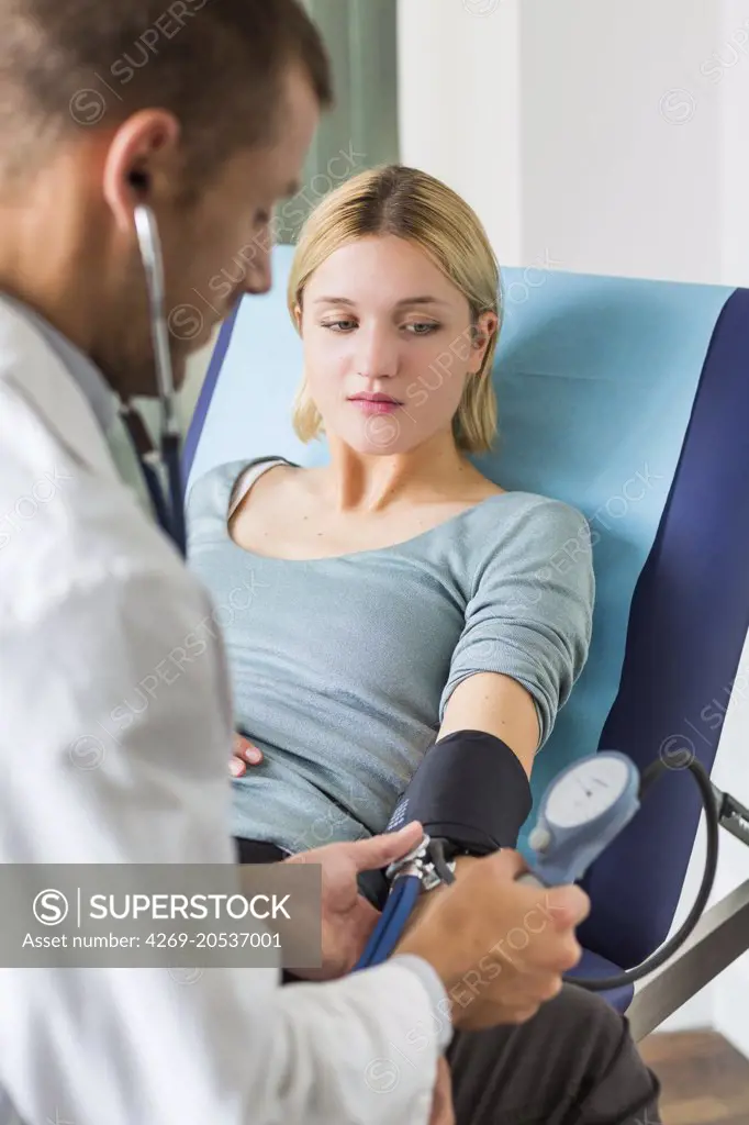 Doctor checking the blood pressure of a woman.