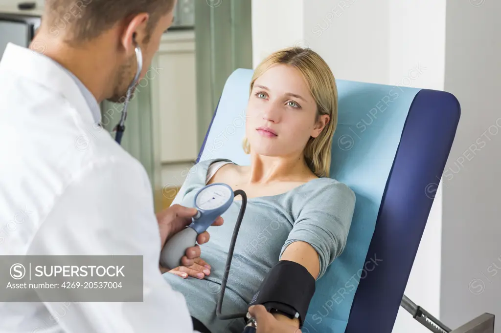 Doctor checking the blood pressure of a woman.