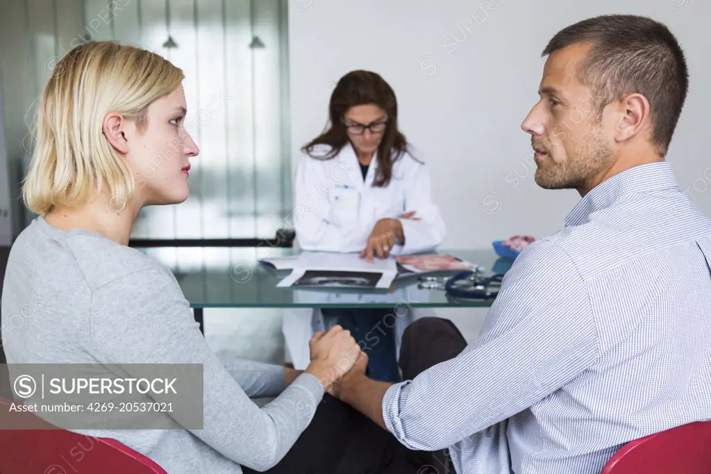 Doctor discussing with a couple during consultation.