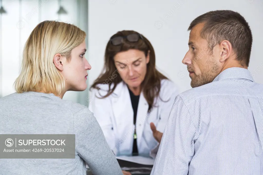 Doctor discussing with a couple during consultation.