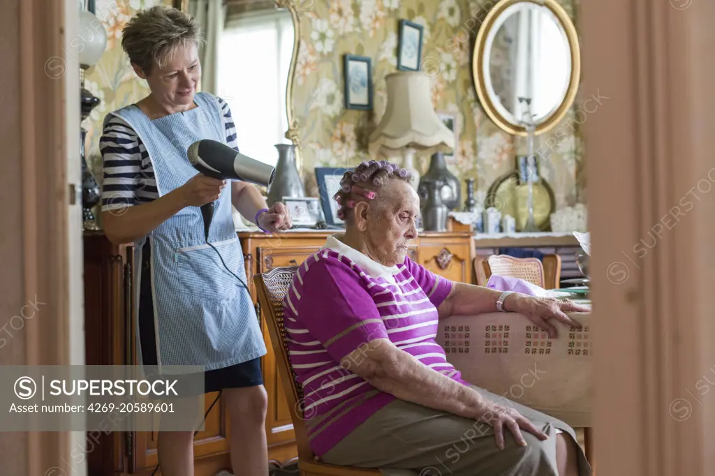 Home care aid assisting elderly woman, Dordogne, France.