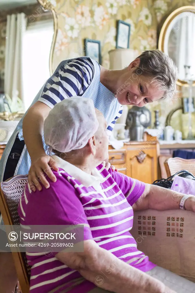 Home care aid assisting elderly woman, Dordogne, France.