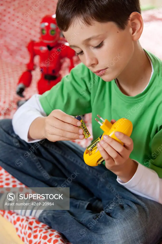 Boy using charger for rechargeable batteries.