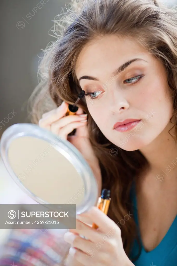 Woman applying mascara on her eyelashes.