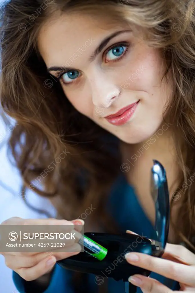 Woman using charger for rechargeable batteries.