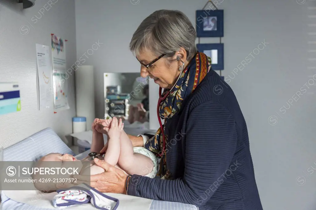 General practitioner with baby, Geveze, France.