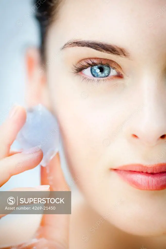 Woman applying icecubes on her face.