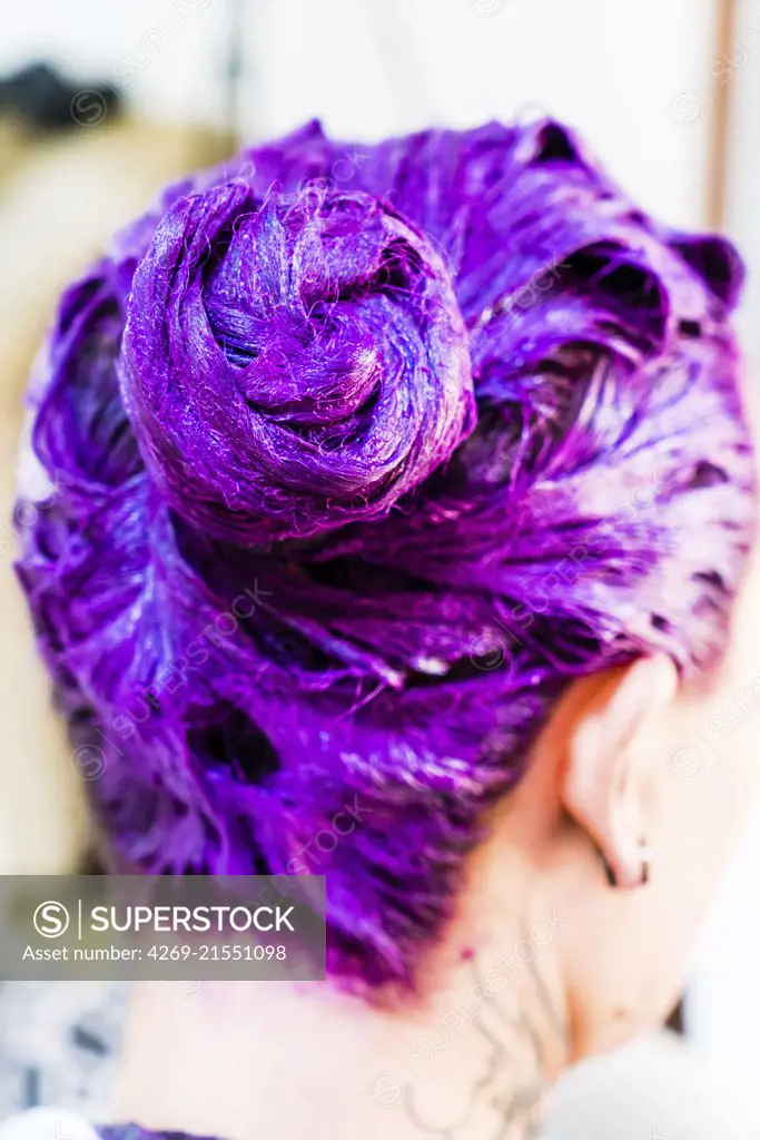Woman applying a purple hair color shampoo.