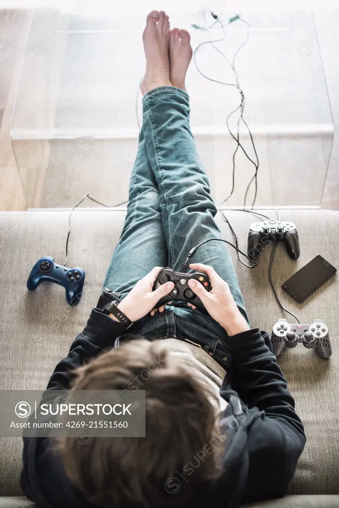 Teenage boy playing a video game using a handheld control.