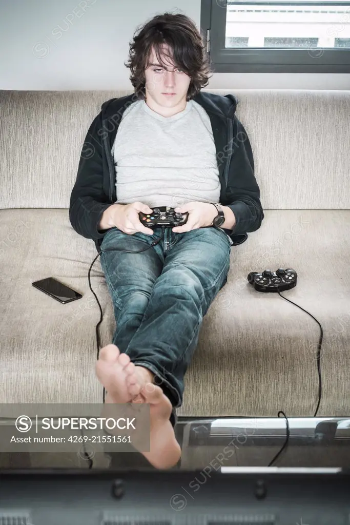 Teenage boy playing a video game using a handheld control.