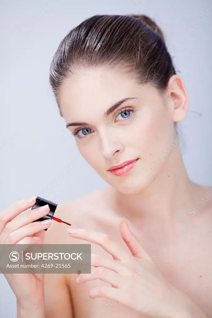 Woman applying polish on nails.