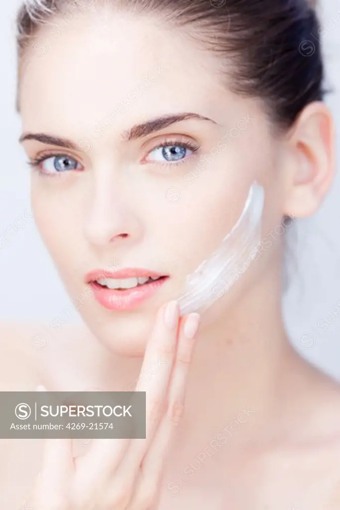 Woman applying moisturizing cream on her face.