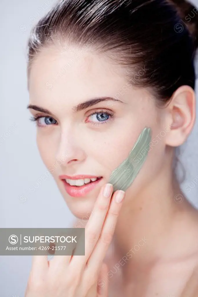 Woman applying green clay cosmetic beauty mask.