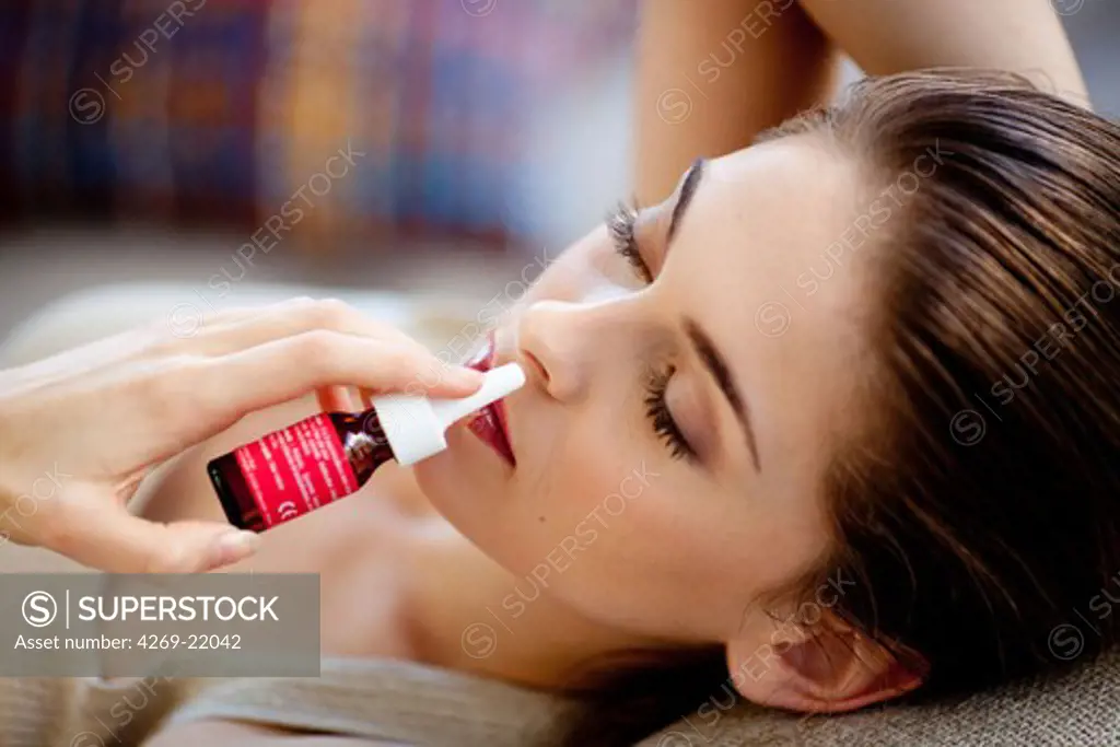 Woman using nasal spray for controlling rhinitis.