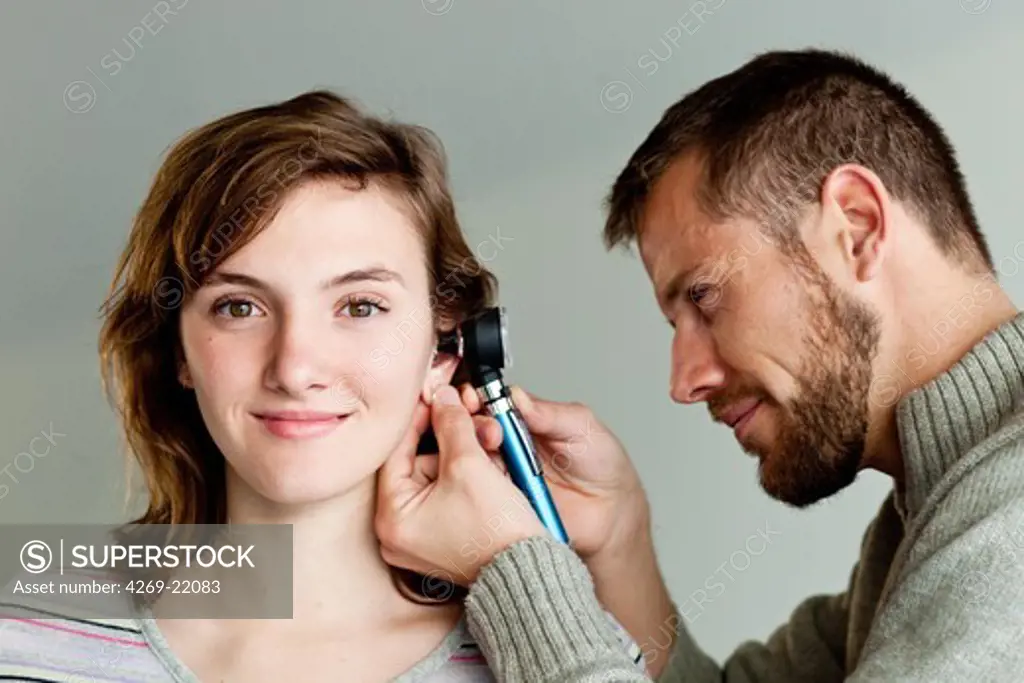 Doctor examining the ears of a patient with an otoscope.