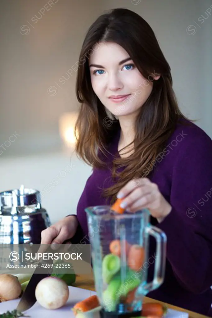 Woman making soup with a blender.