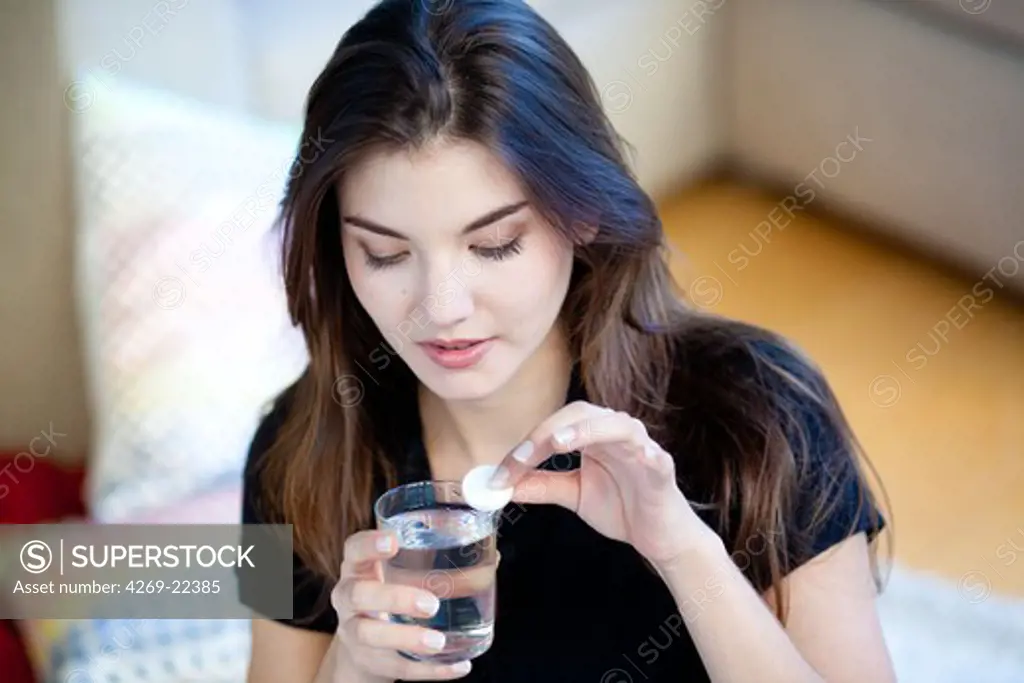 Woman taking an effervescent aspirin tablet.