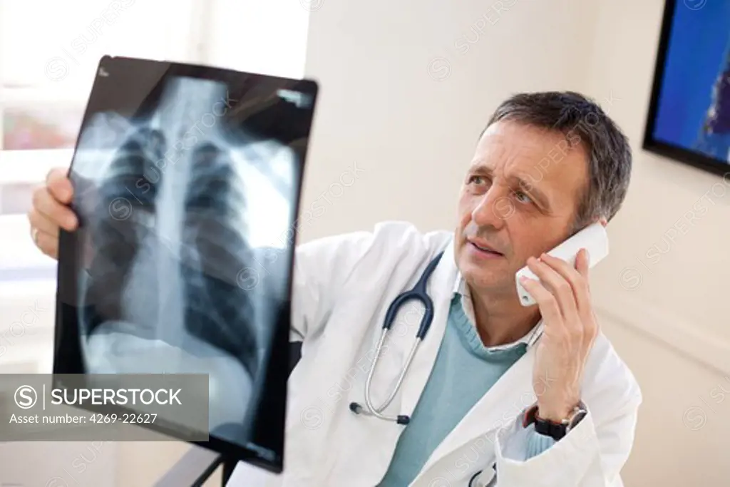 Doctor commenting lung X-rays on the phone.