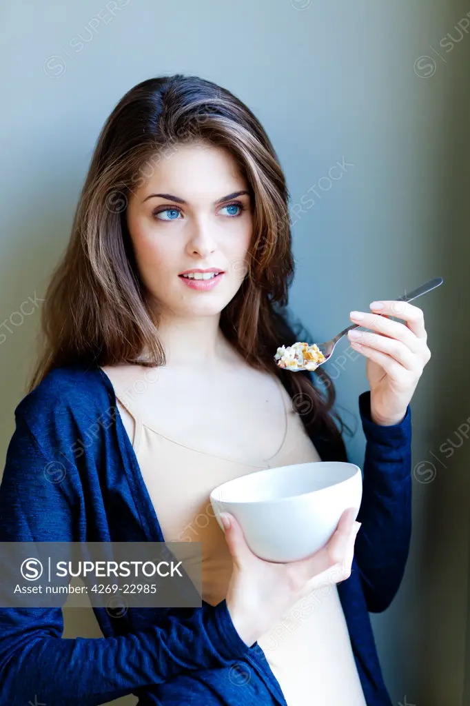 Woman eating muesli (cereals).