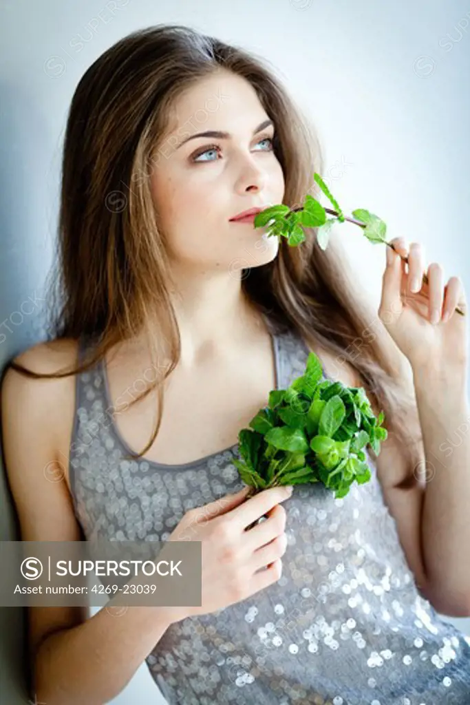 Woman smelling mint leaves (Mentha sp.).