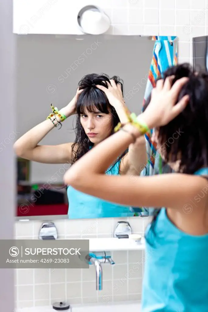 Young woman checking her face in the mirror.