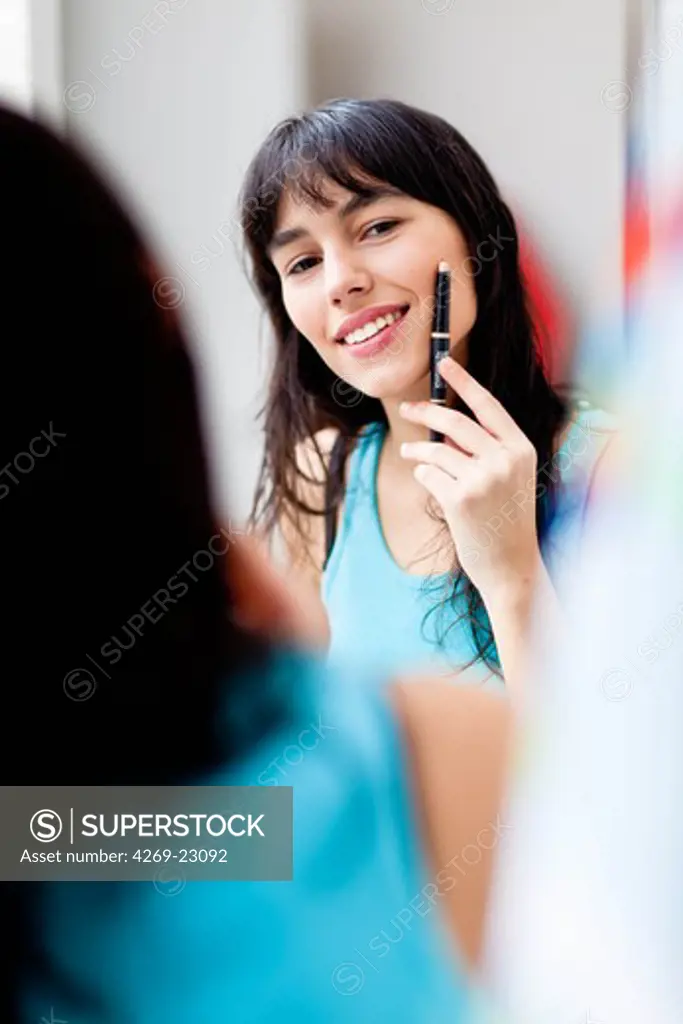 Young woman applying make-up foundation.