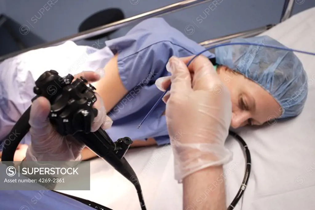 Gastroenterologist performing a gastrointestinal fiberoptic endoscopy. He inserts in the fiberoptic endoscope a polypus forceps allowing the ablation of polypus during the examination.
