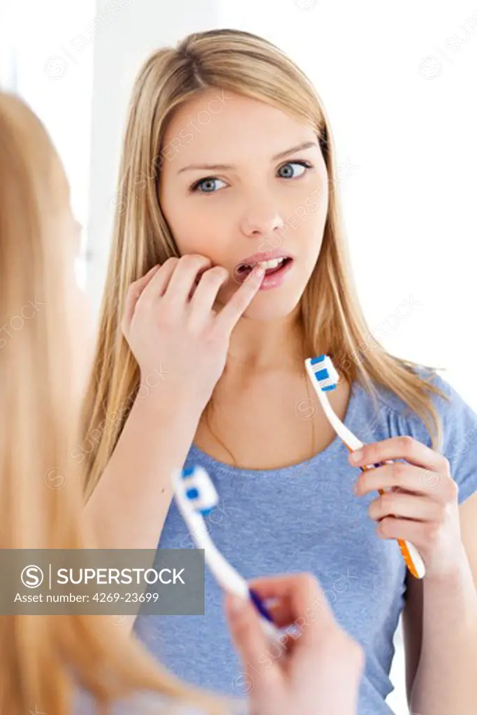 Woman brushing her teeth with toothbrush.