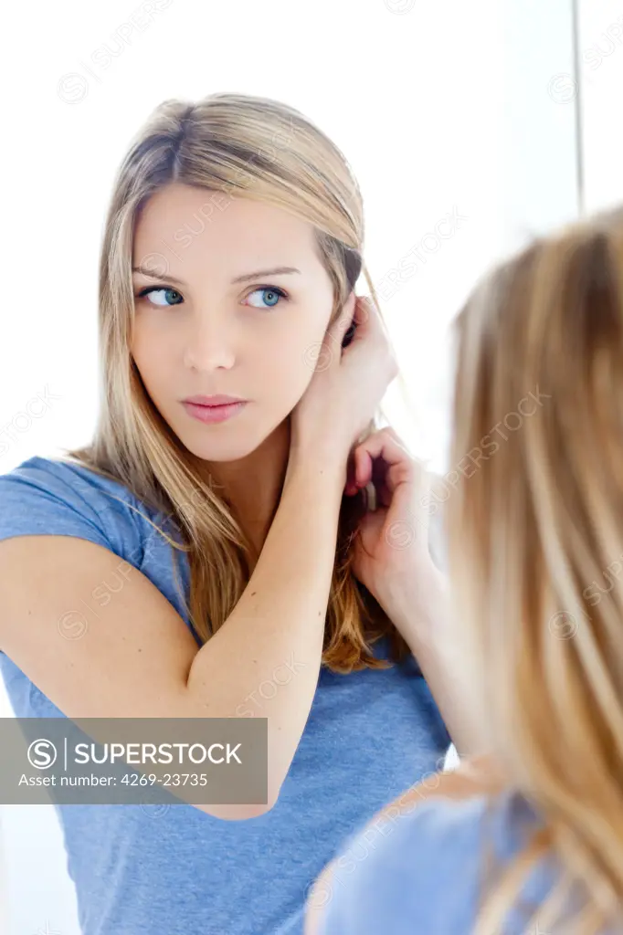 Young woman checking her face in a mirror.