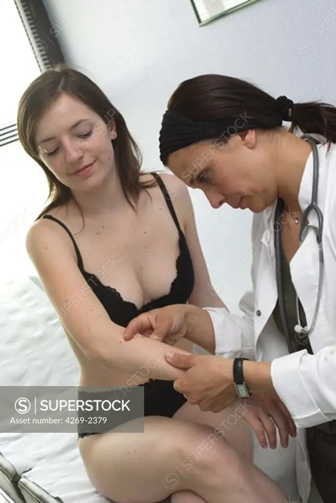 Dermatologist examining the beauty mark of a patient for melanoma screening.