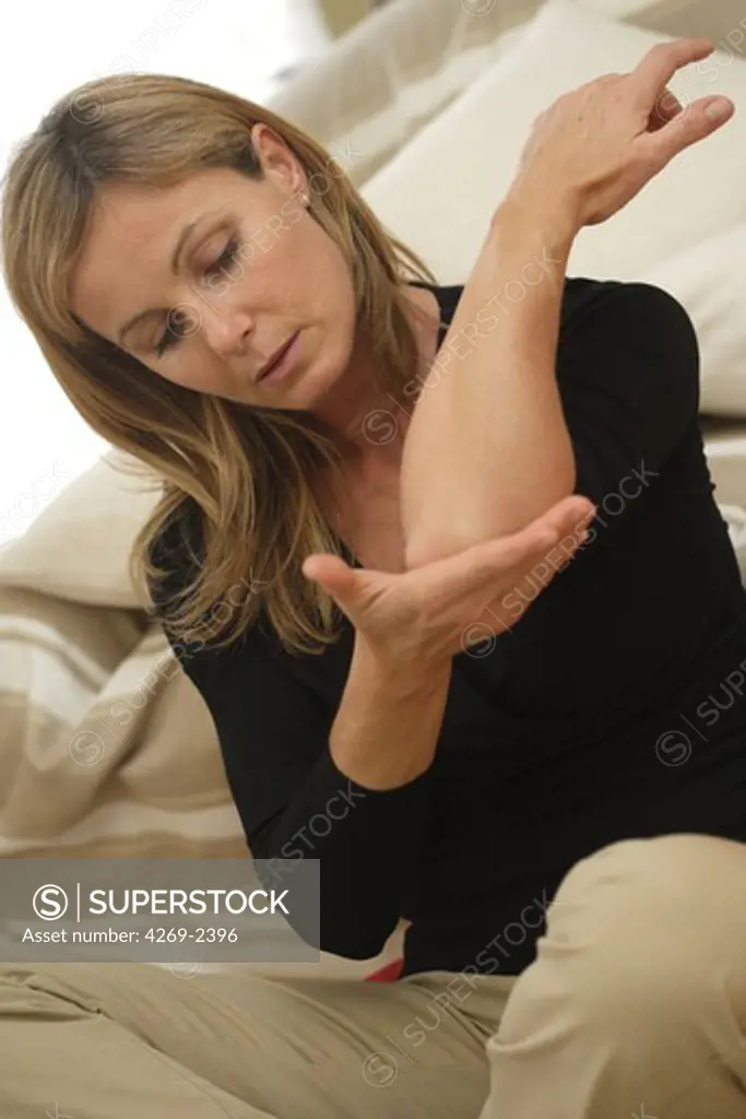 Woman suffering from an articular pain in the elbow (tennis elbow).