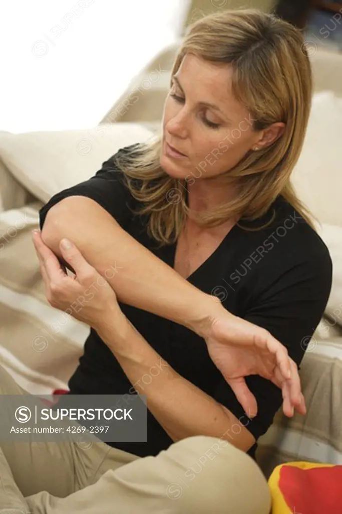 Woman suffering from an articular pain in the elbow (tennis elbow).