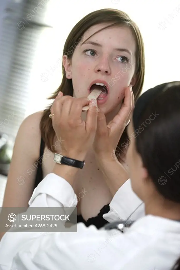 Female doctor examining the throat of a female patient.