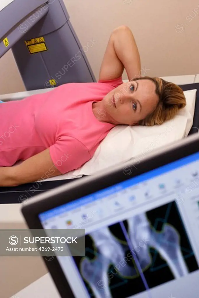A doctor uses a bone densitometer to measure the optical density of the neck of the femur of female patient to diagnose osteoporosis.