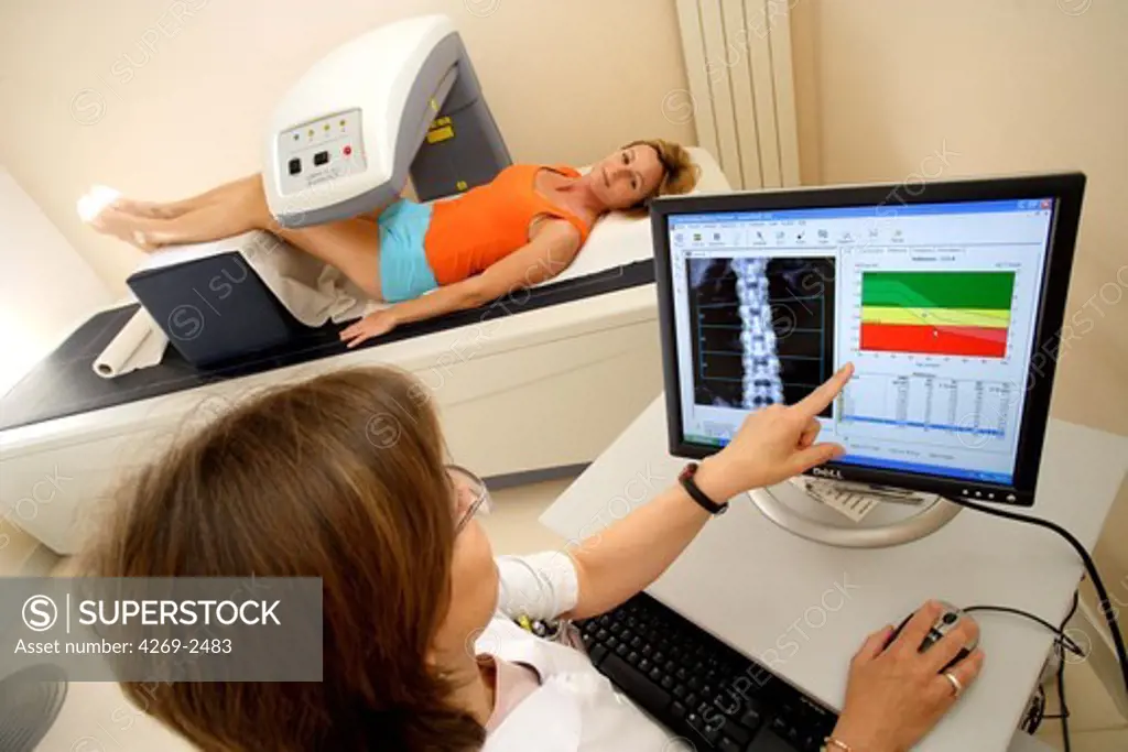 A doctor uses a bone densitometer to measure the optical density of the lower rachis (backbone) of female patient to diagnose osteoporosis.