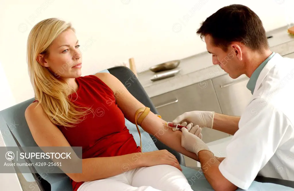 Blood sampling. Doctor taking a blood sample from a female patient.