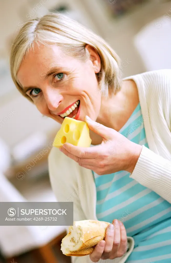 Food. Mid-age woman eating cheese.