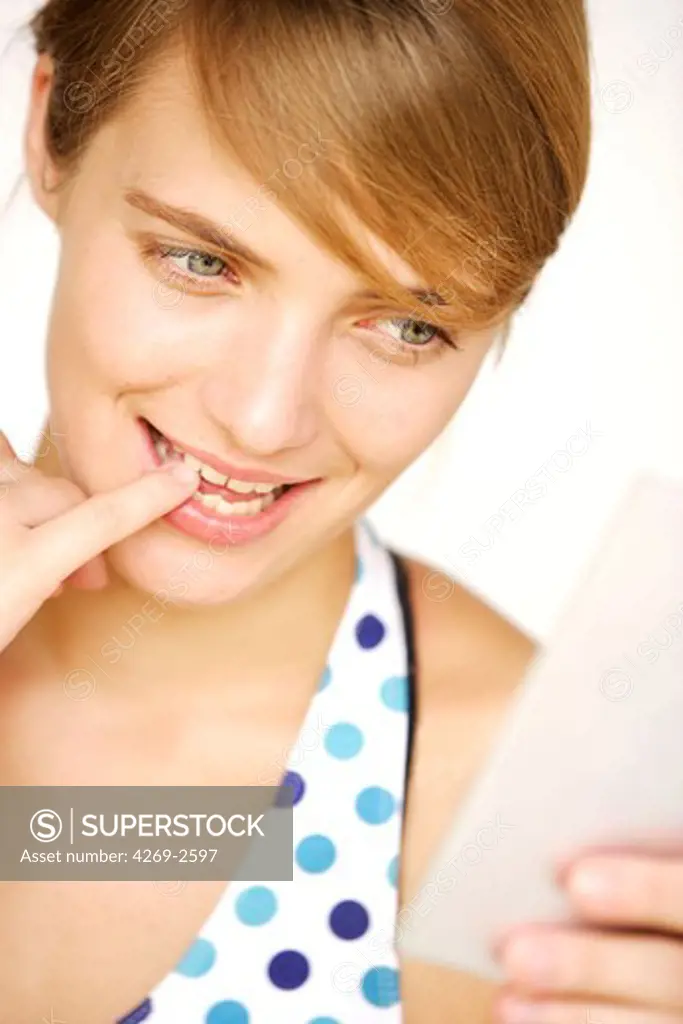 Young woman checking her teeth in a mirror.