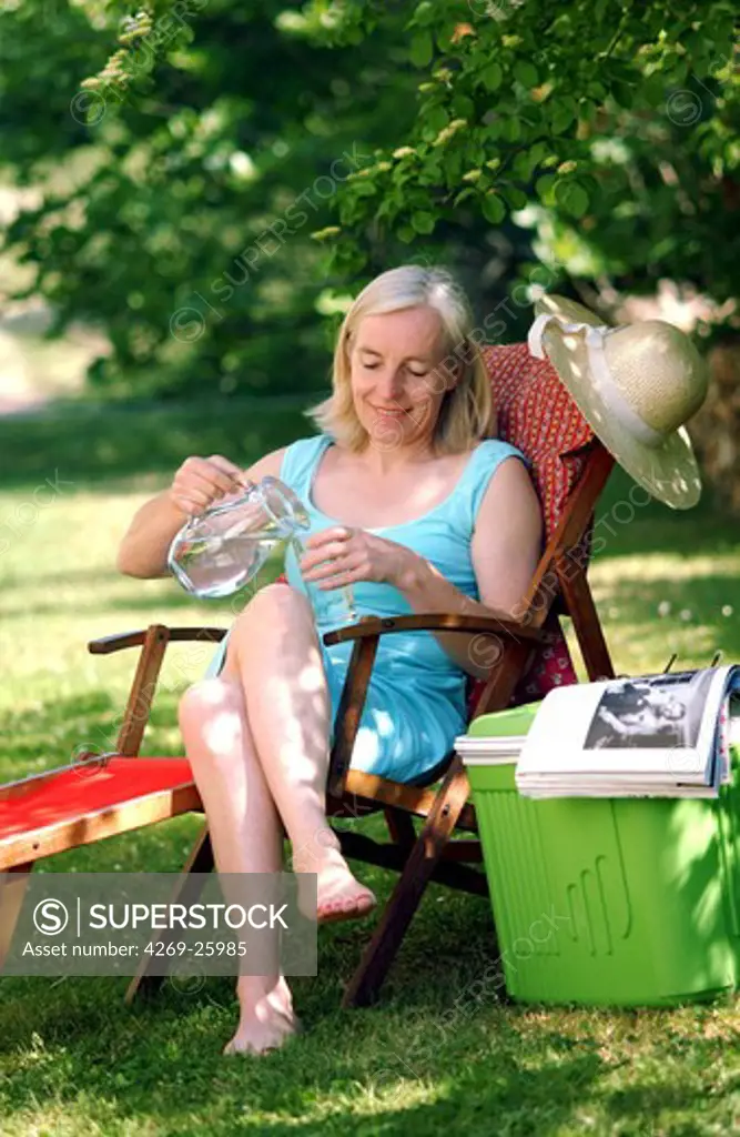 Senior woman. Woman using an icebox to keep water cold in hot weather.