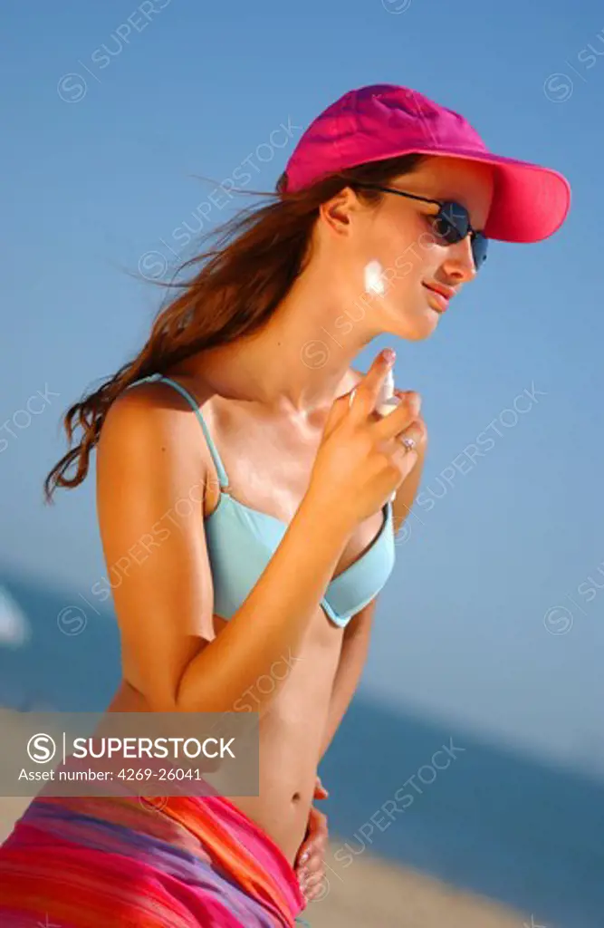 Sun. Woman applying sunblock at the beach.