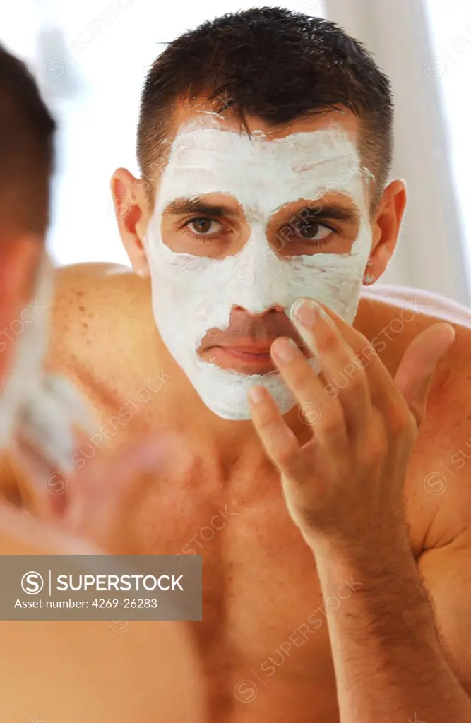 Man. Man applying a cosmetic beauty mask on his face.