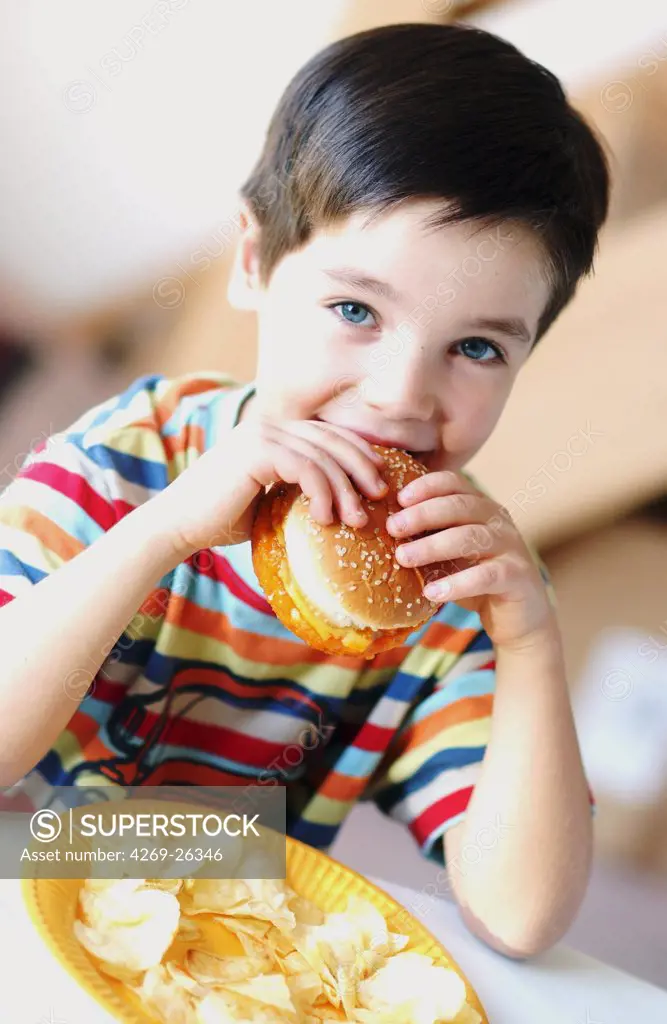 Food. 6 years old child eating a hamburger.