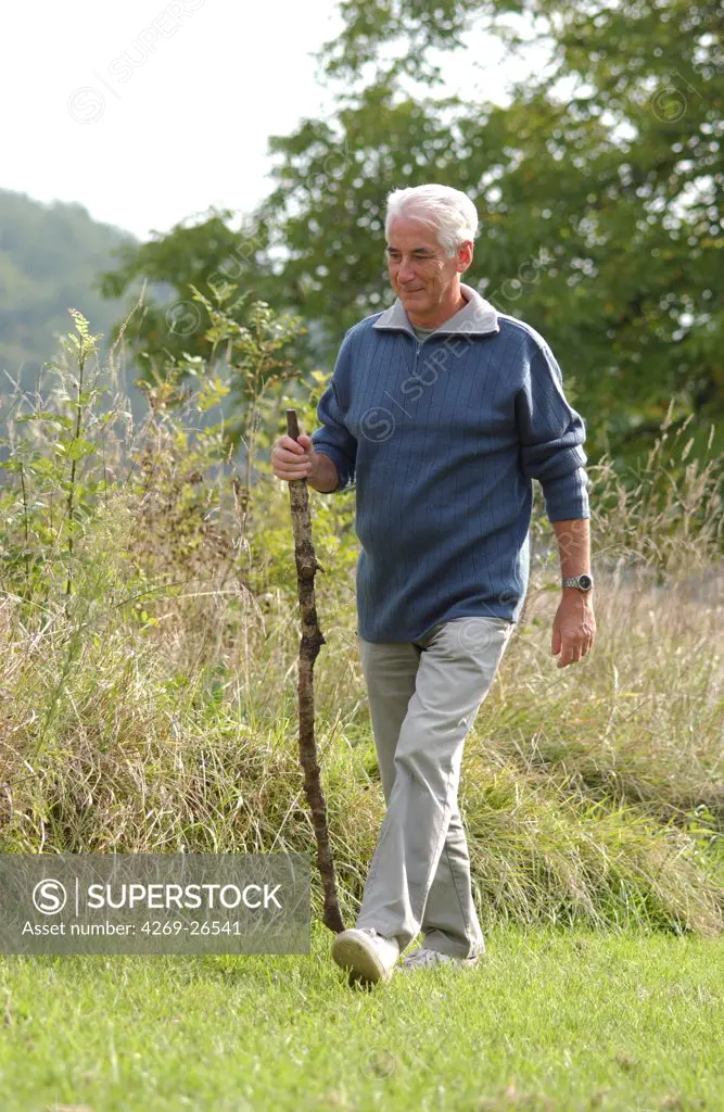 Man. 60 years old man walking in the countryside.