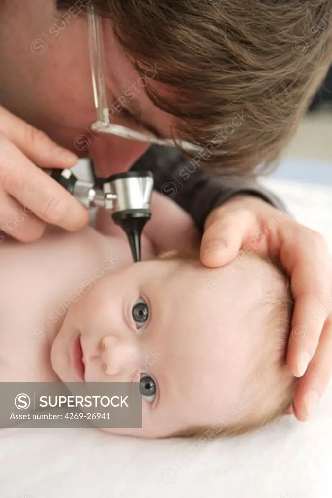 Medical consultation. A pediatrician examines the ears of a 2 months old baby with an otoscope.