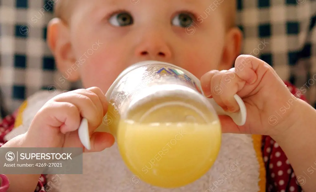 Baby. 13 months old baby drinking orange juice.